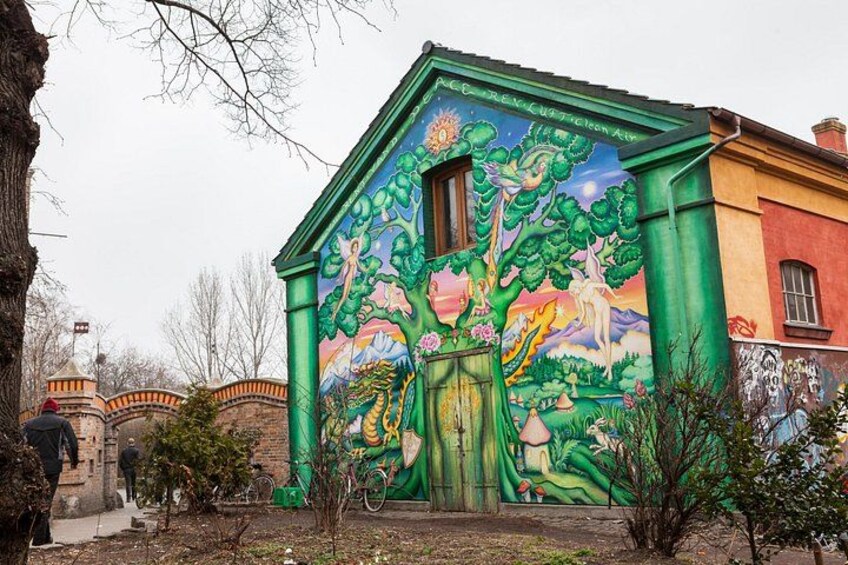 A colorful mural on a building, a bicycle, and a tree. 3