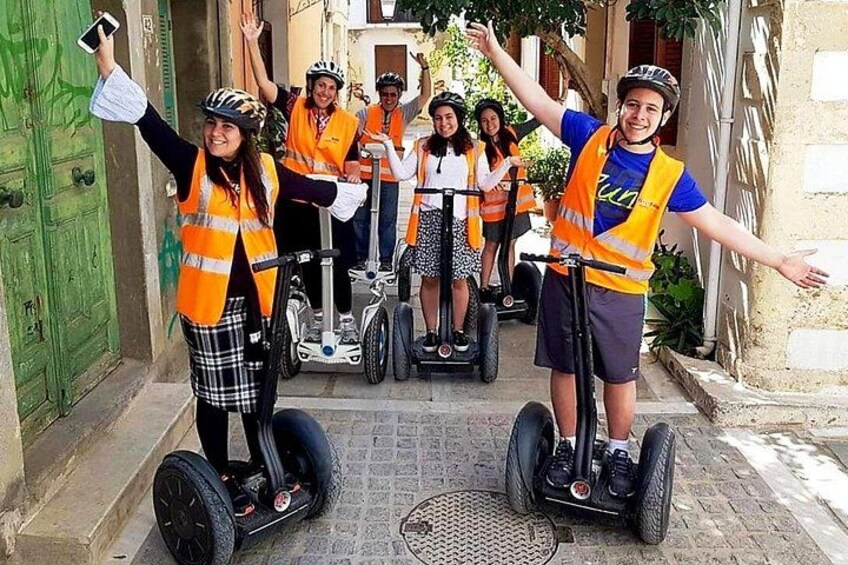 Mensen op segways, met veiligheidsvesten, in een open landschap met stenen gebouwen. 1