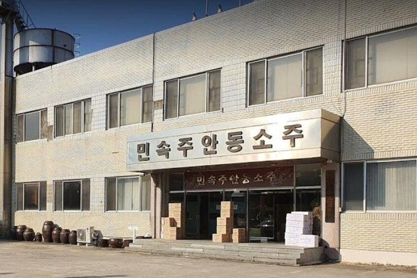 A building with a sign in Korean, large windows, and some items outside. 4