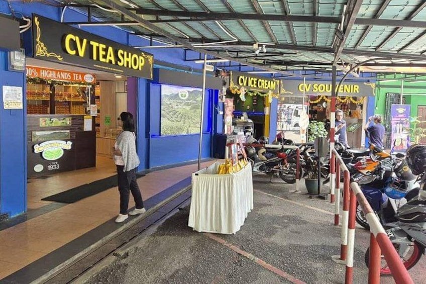 Ett tehus som heter CV Tea Shop, med en skylt, en motorcykel parkerad utanför och ett bord med varor utställda. 3