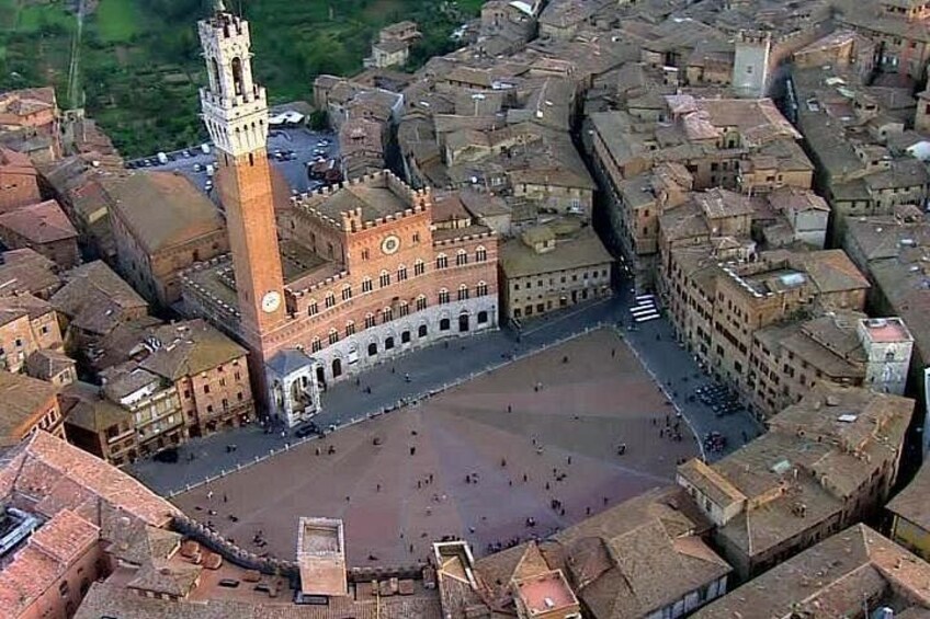 An aerial view of a historic town with a prominent square, a tall tower, and surrounding buildings. 4