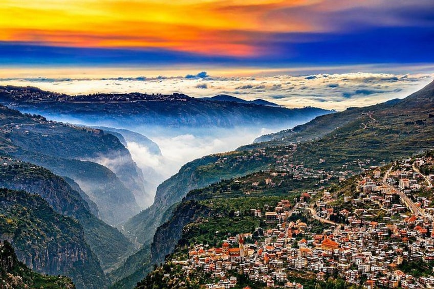 A mountainous landscape with a town nestled in a valley, a waterfall, and a dramatic sky. 3