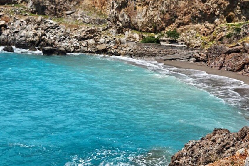 Un paysage côtier caractérisé par une eau turquoise et limpide, des falaises rocheuses et une plage de sable. 4