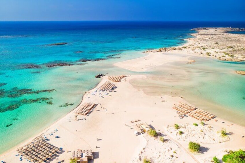 A beach with clear turquoise waters, sandy shores, and sun loungers. 4