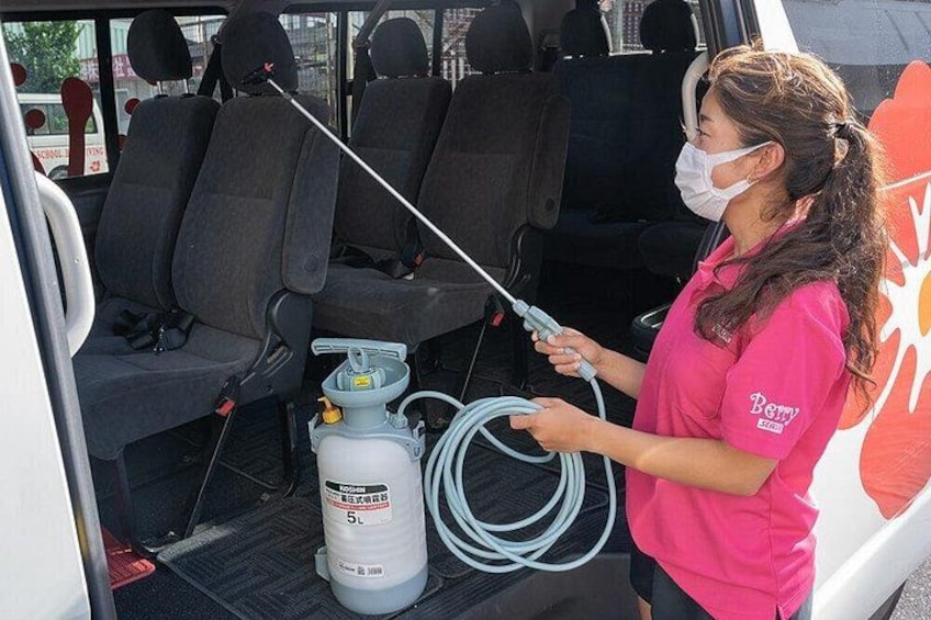A person in a pink shirt cleaning a vehicle with a spray bottle and hose. 2