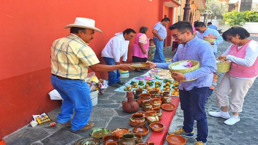 A street market with vendors selling pottery and fruits. 4