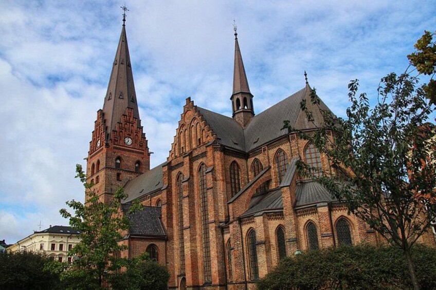 A large brick church with two prominent spires and a clock tower. 3