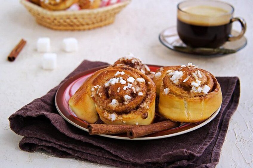 Cinnamon rolls on a plate with a cup of coffee and marshmallows in the background. 2