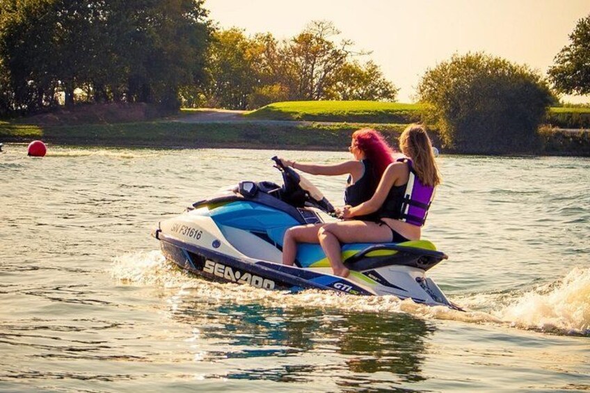 Two people on a jet ski with water splashing behind them. 3