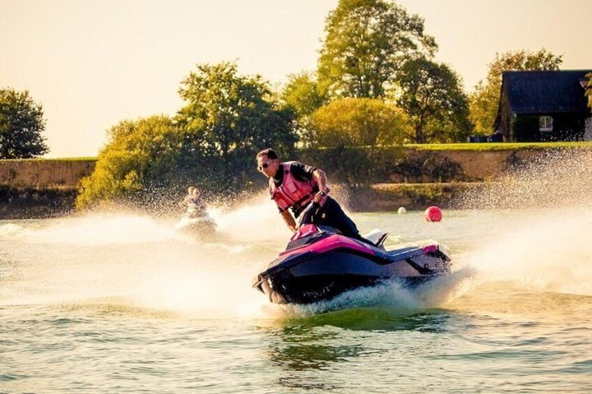 A person jet-skiing on a body of water with trees and a house in the background. 4