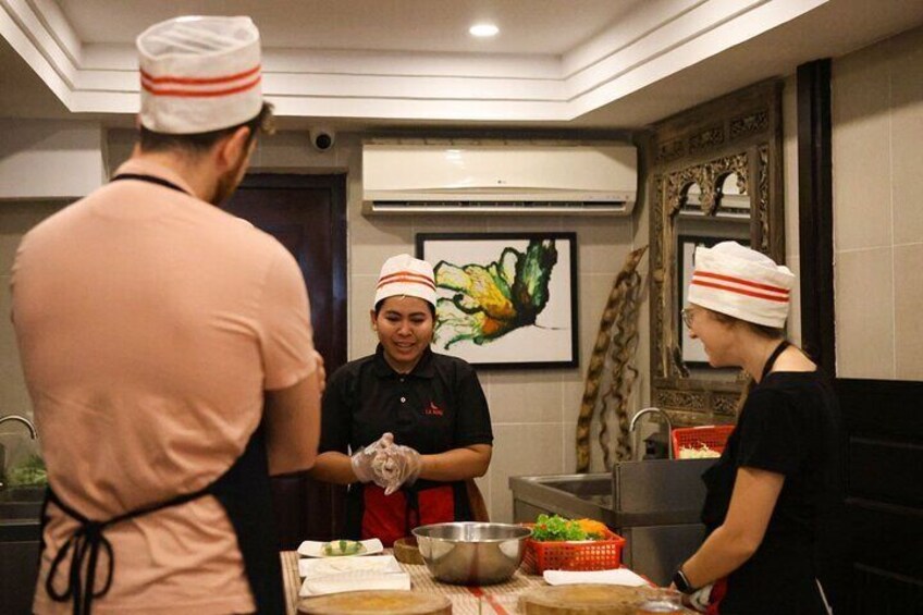 Une cuisine où trois personnes, portant des toques de chef, préparent des plats. 2