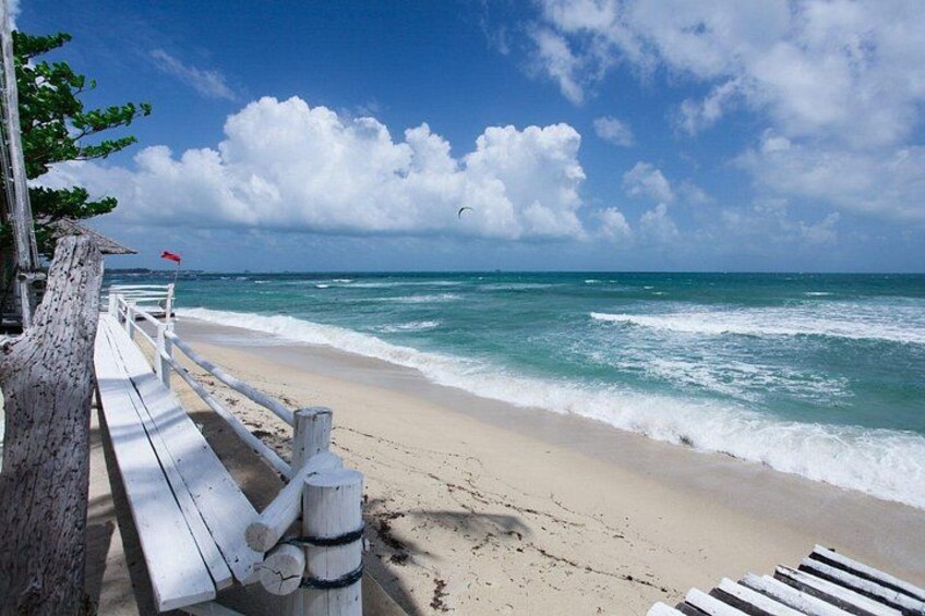 A wooden pier leading to a sandy beach with ocean waves. 5