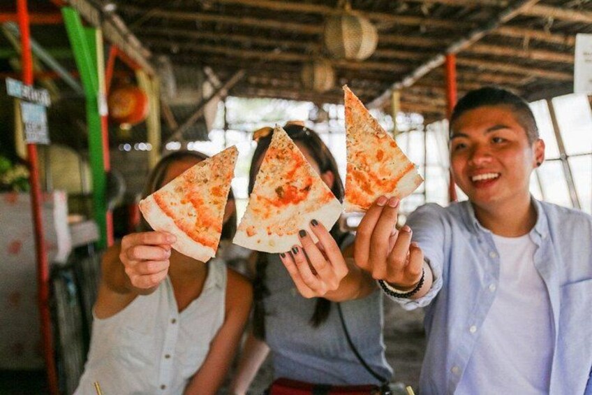 Three people holding slices of pizza in a casual setting. 3