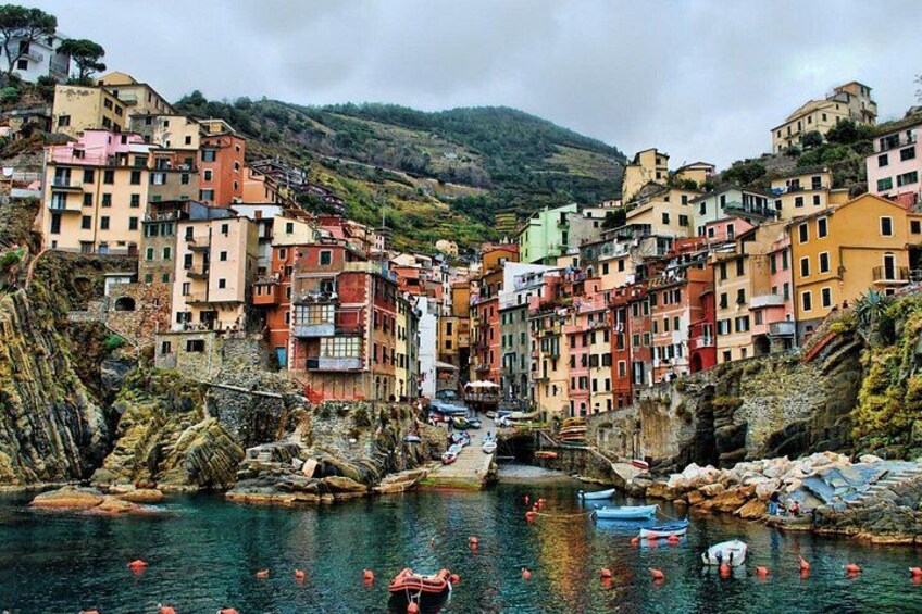 Un village côtier aux bâtiments aux couleurs vives, avec une côte rocheuse et des bateaux sur l’eau. 3