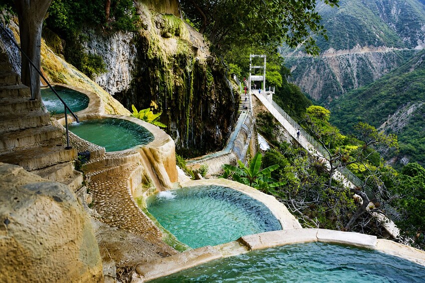 Una serie de piscinas escalonadas con una escalera que lleva a una plataforma panorámica. 4