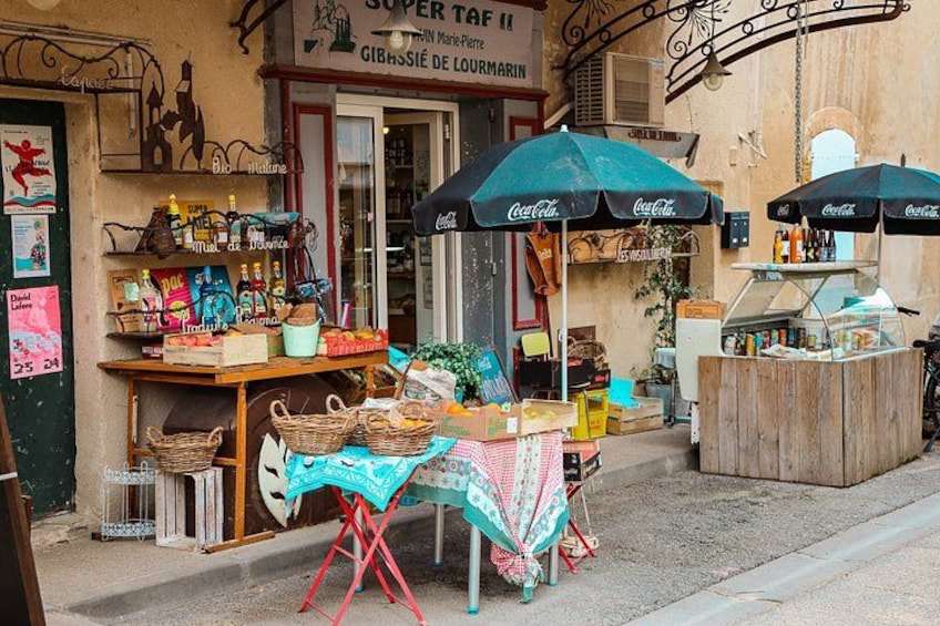 A street market stall with a Coca-Cola umbrella, a wooden table, and various items for sale. 5