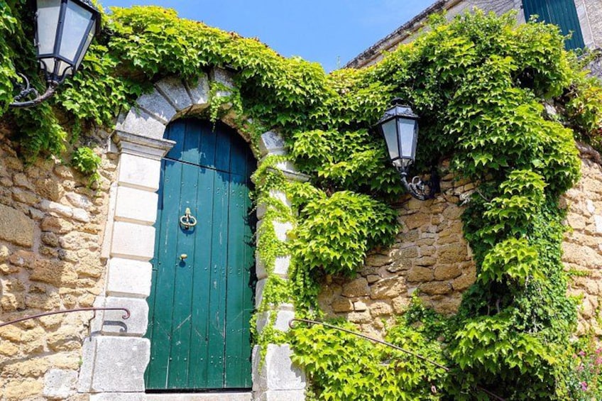A green door with a knocker, a stone wall, and a lamp post. 2