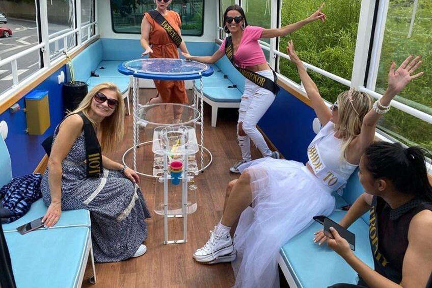 A group of people on a boat with blue seating and a small table with drinks. 4