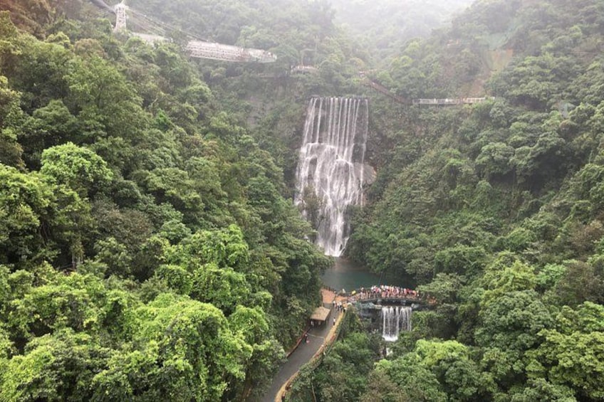 A large waterfall cascading down a lush green valley with a viewing platform at the base. 3