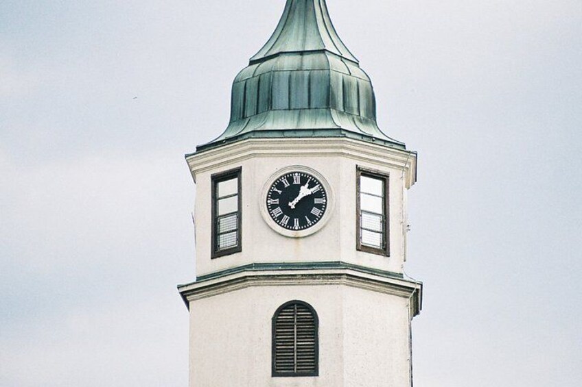A clock tower with a green roof and a white facade. 4