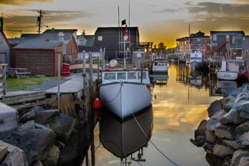 Un port avec des bateaux amarrés, des bâtiments et un coucher de soleil. 1