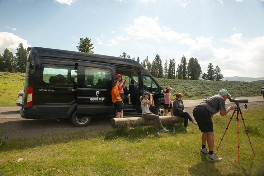 A black van with 'good trip' written on it, parked on a grassy roadside with a scenic landscape in the background. 4