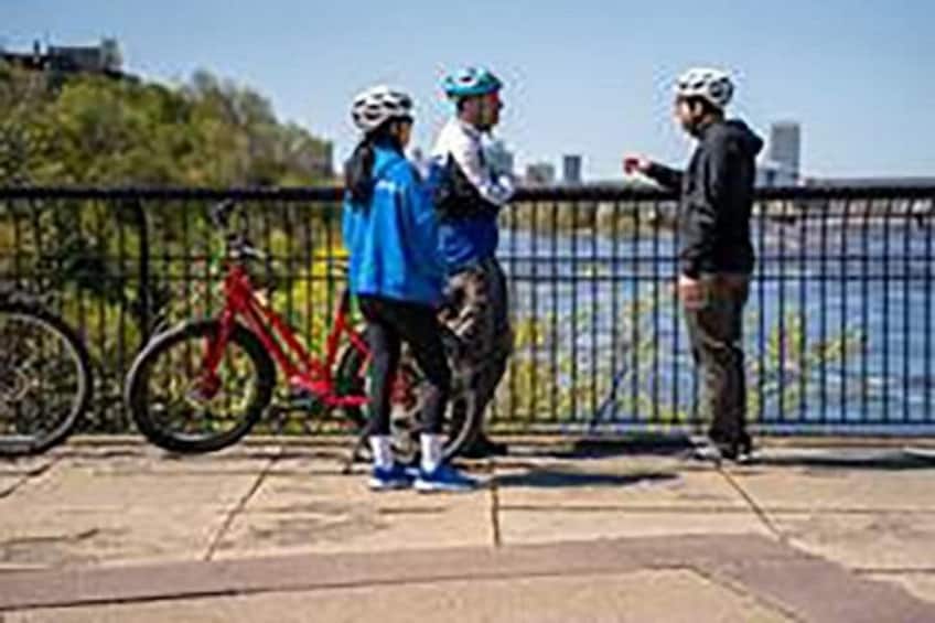 Trois personnes se trouvent sur un pont, dont une avec un vélo. 3