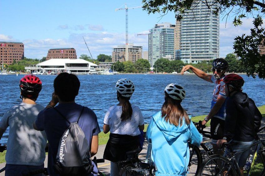 Un groupe de cyclistes se trouve au bord de l’eau, avec des bâtiments et une grue en arrière-plan. 5