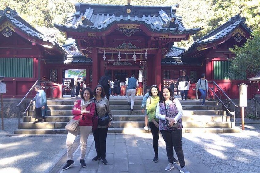 A traditional Japanese temple with red and green structures, a staircase, and people around. 5