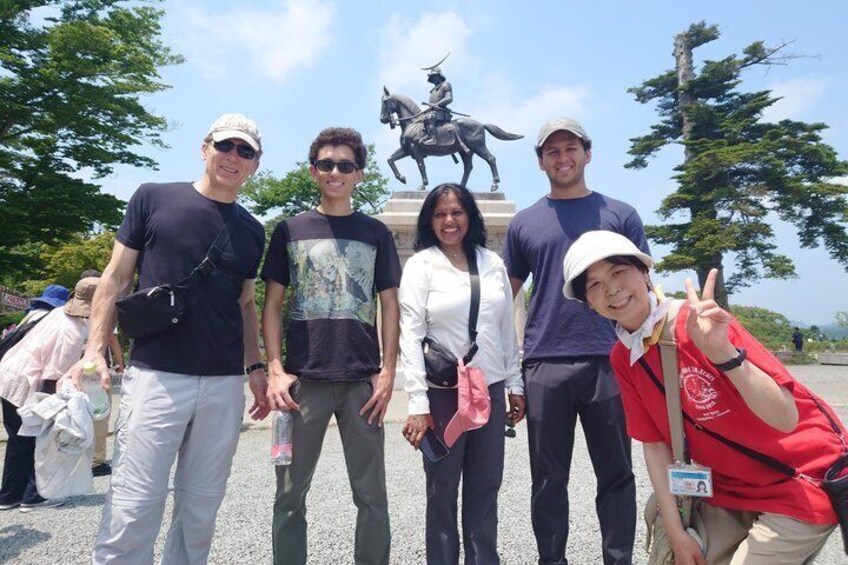 A group of people posing in front of a statue. 1