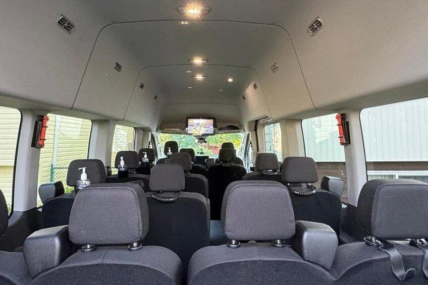 The interior of a vehicle with multiple rows of seats and a rearview mirror. 2