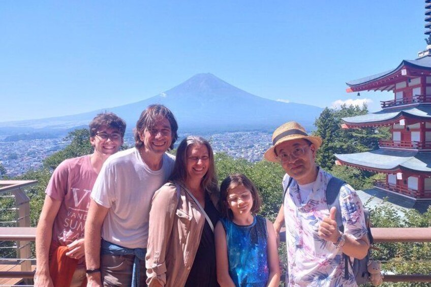 Un grupo de personas en un balcón, con vista a una montaña y arquitectura japonesa tradicional. 1