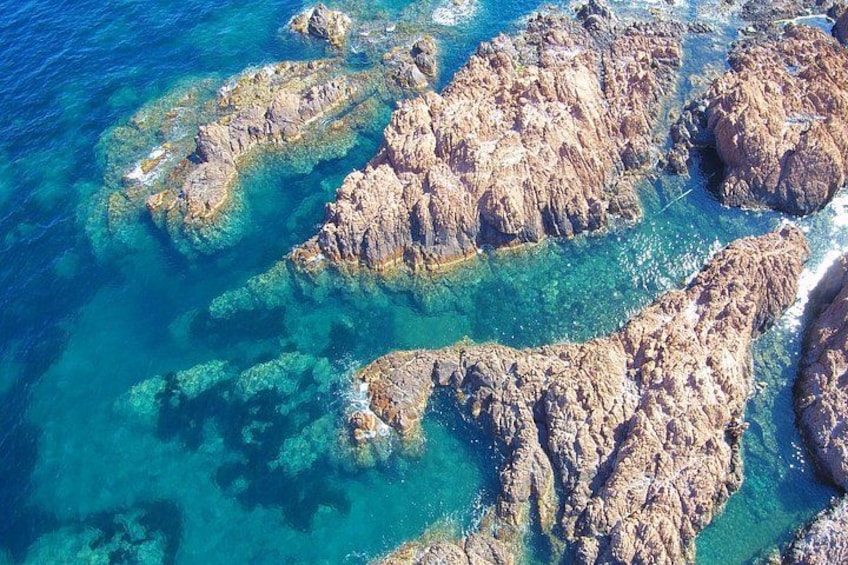 A rocky coastline with clear blue waters and shallow areas. 1