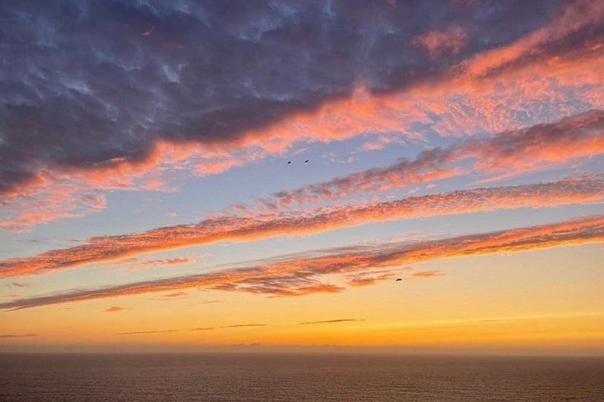 Un coucher de soleil sur l’océan, avec des nuages et un horizon dégagé. 2