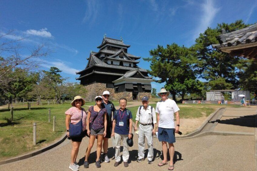 Eine Gruppe von Personen steht vor einem traditionellen japanischen Gebäude mit einem gewölbten Dach. 1