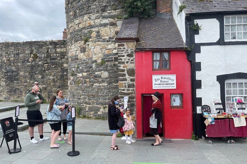 A red building with a sign, a stone wall, and a small market stall. 3