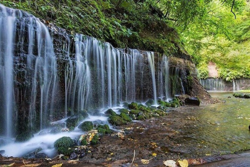 A waterfall cascading over moss-covered rocks into a shallow stream. 4