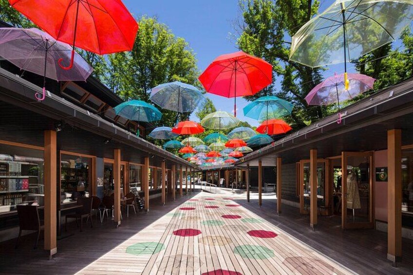 A covered outdoor walkway with colorful umbrellas overhead and a patterned floor. 5