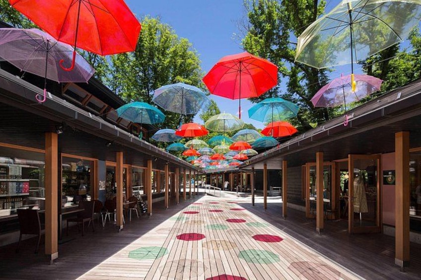A covered walkway with colorful umbrellas overhead and a patterned floor. 5