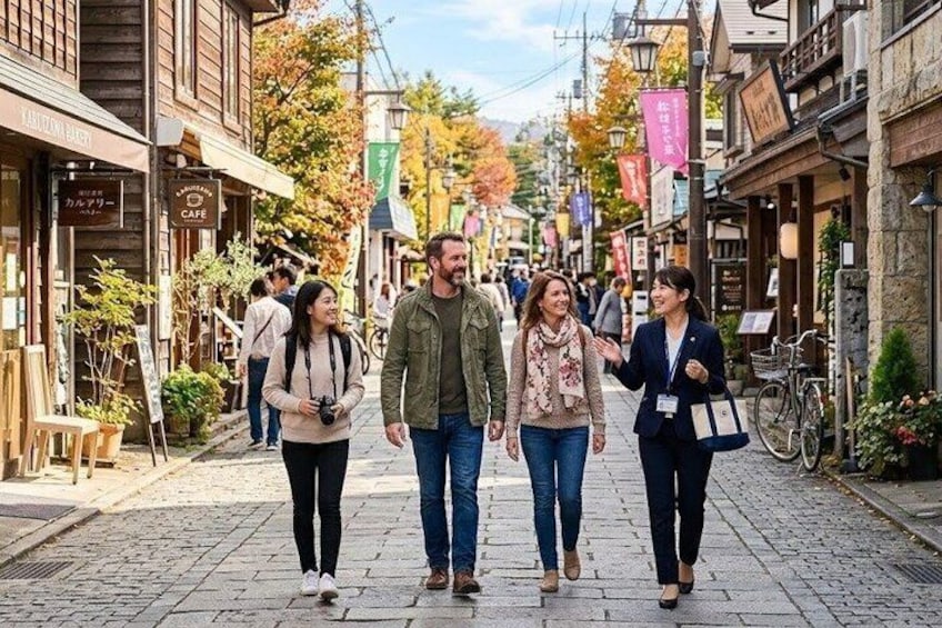 A cobblestone street lined with shops and cafes, pedestrians walking, and autumn foliage. 2