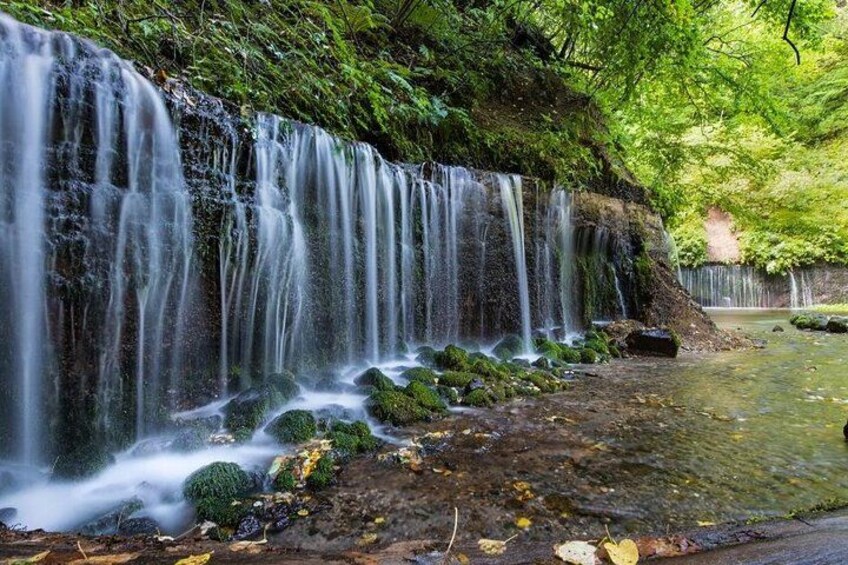 A waterfall cascading over moss-covered rocks into a clear pool. 4