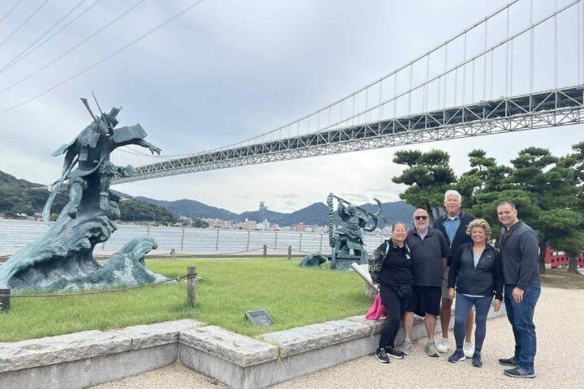 A group of people near a sculpture and a bridge. 1