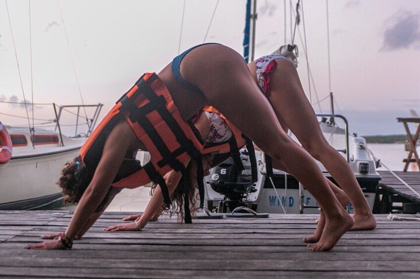 A person performing a yoga pose on a wooden dock with boats in the background. 5