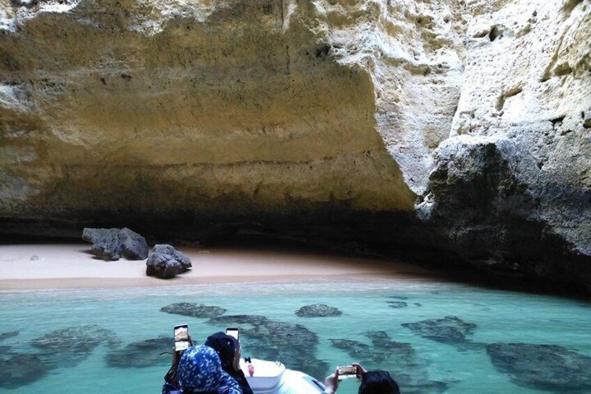 A cave with a sandy beach and clear turquoise water. 2