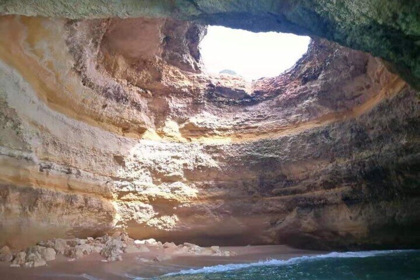 A natural rock formation with a cave entrance and a view of the ocean. 3
