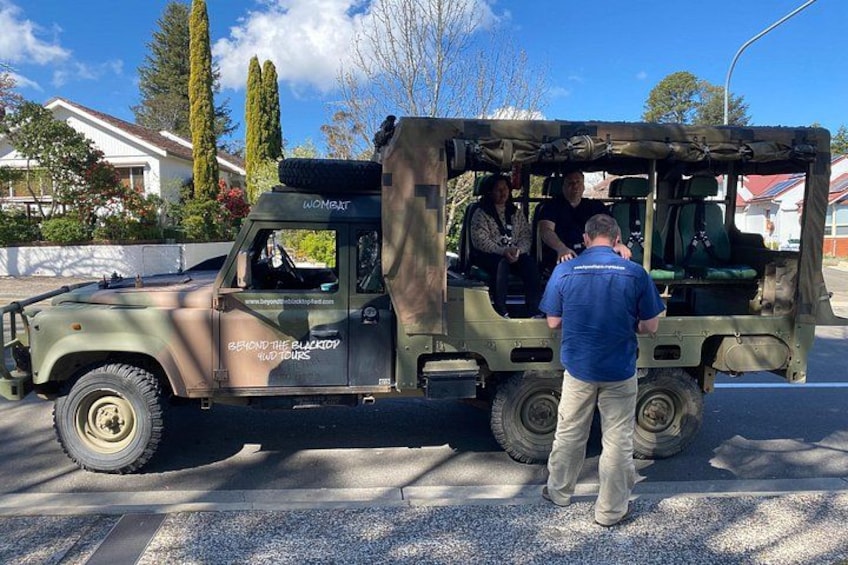 A military-style vehicle parked on a street with a person standing in front of it. 5
