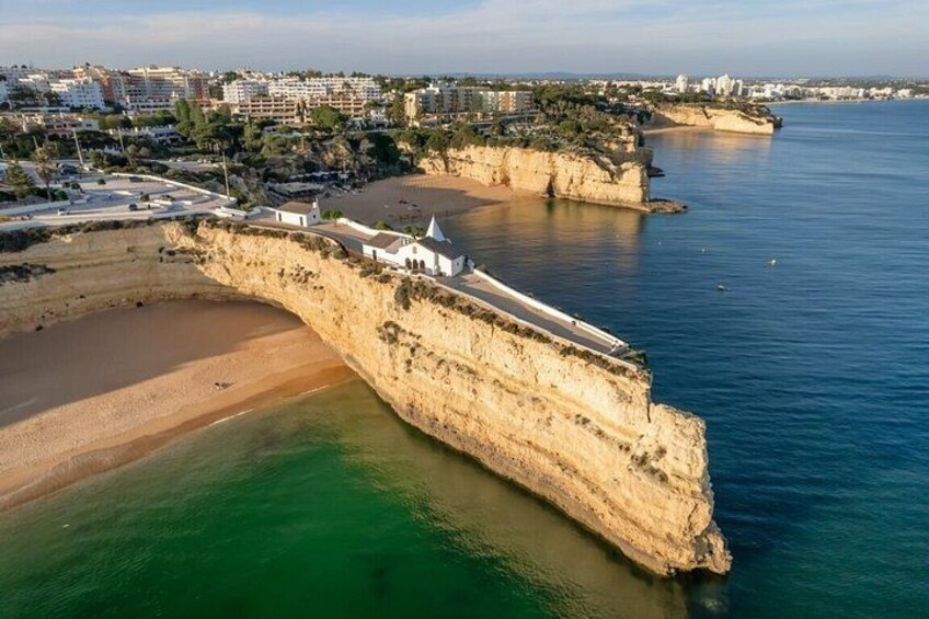 A coastal cliff with a beach, a fortified structure, and a cityscape in the background. 3