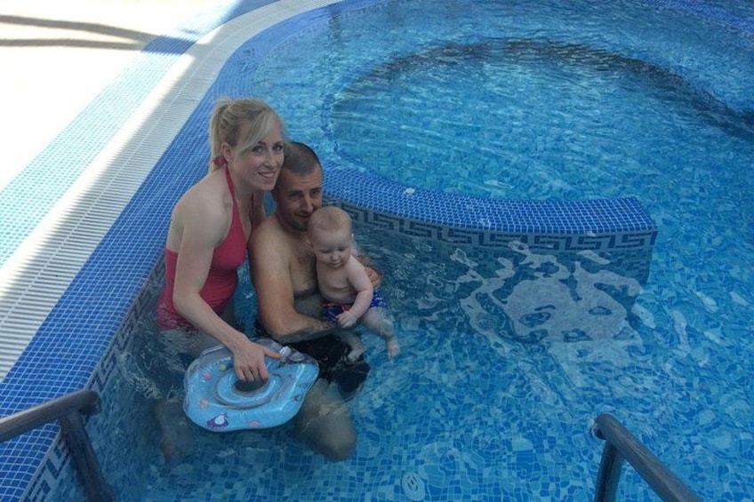 A swimming pool with a tiled edge and a person sitting in the water. 3