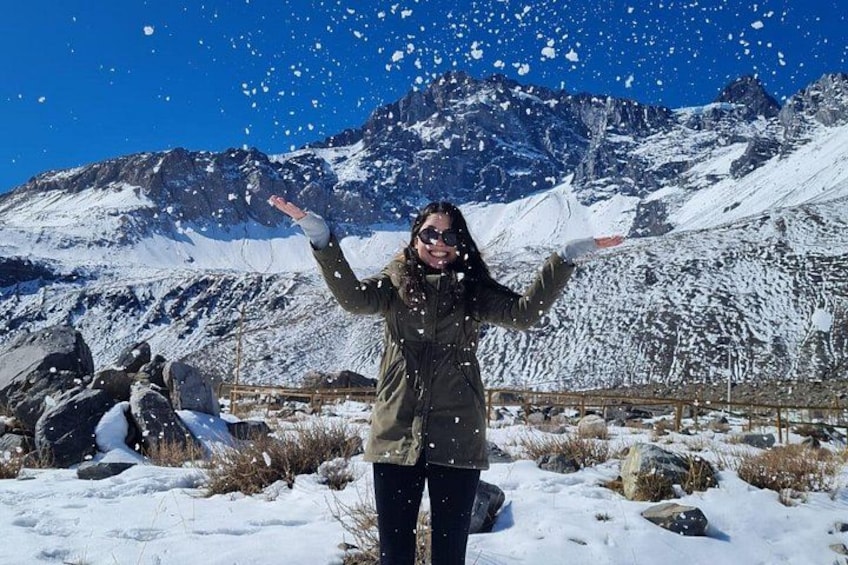 Eine Person steht in einer verschneiten Landschaft mit Bergen im Hintergrund. 1