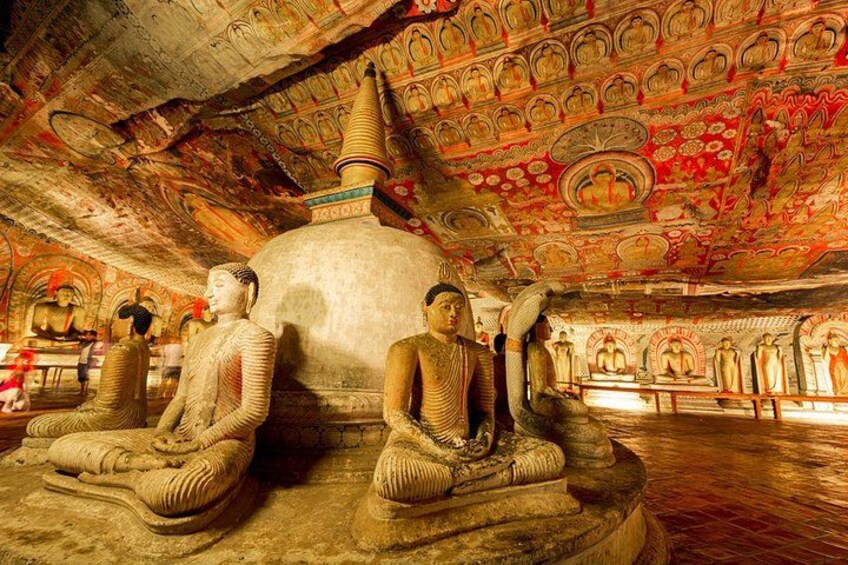 Een groot Boeddhabeeld in een tempel met gedetailleerde plafonddecoraties en andere beelden. 1